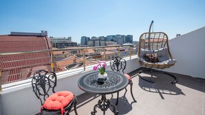 A rooftop terrace with a round table, two chairs, a hanging chair, and a view of the cityscape. - Grand Palace Hotel (Istanbul)