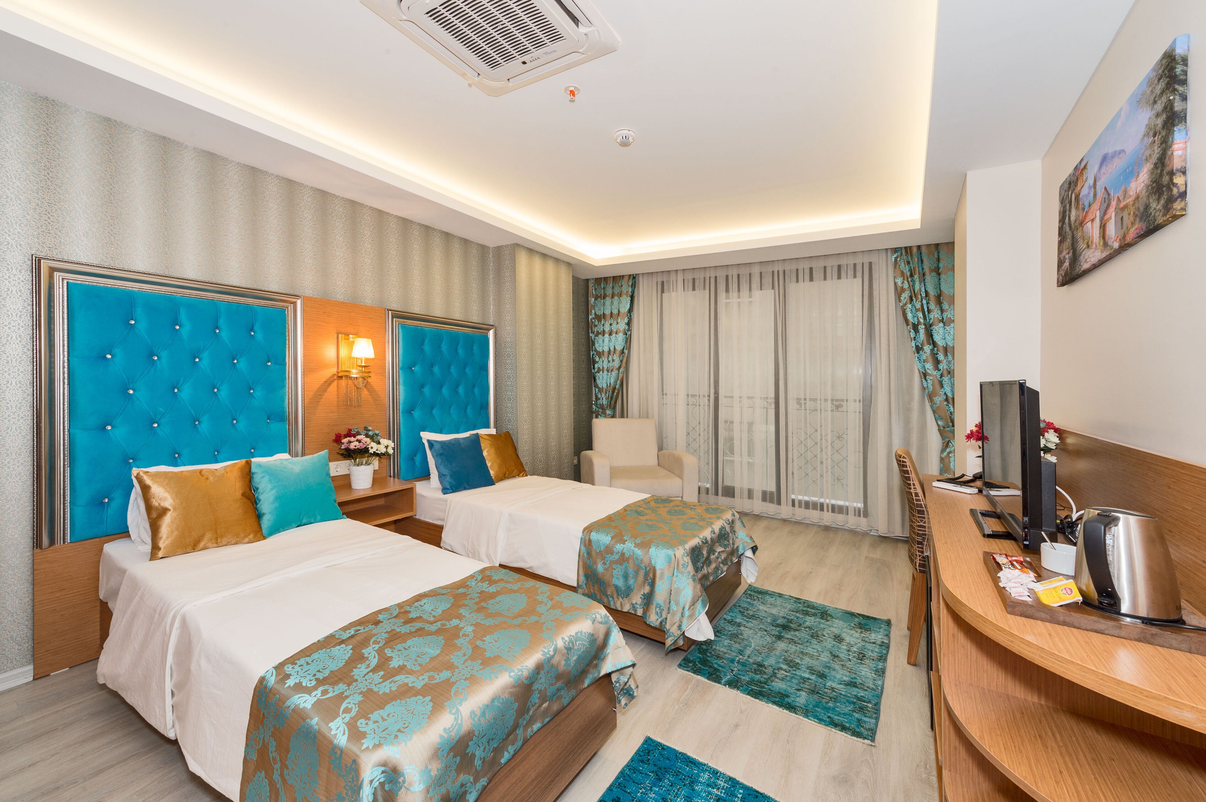A hotel room with two beds, a desk, a chair, and a TV.