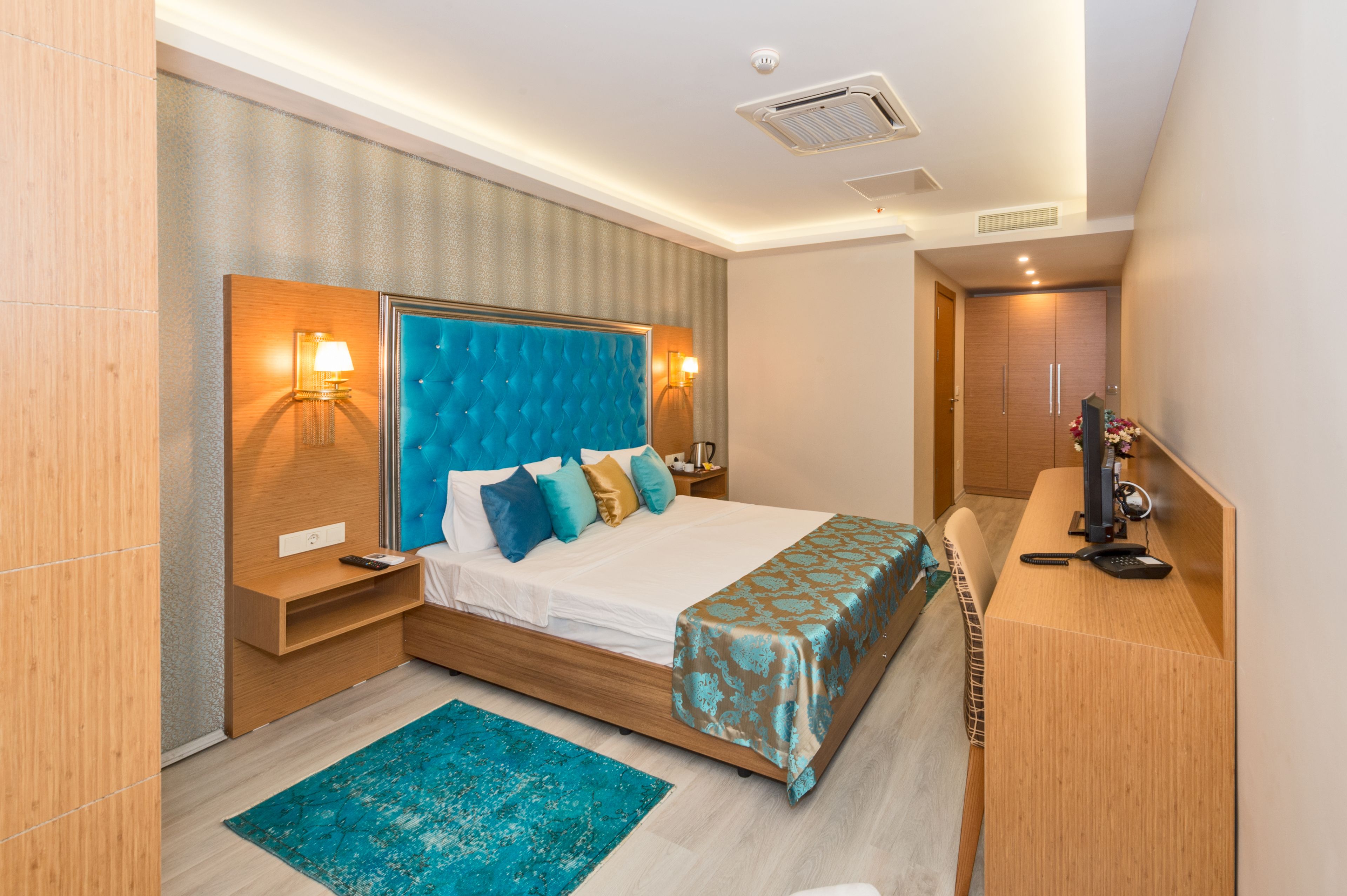 A modern hotel room with a large bed, bedside tables, a desk, and a chair.