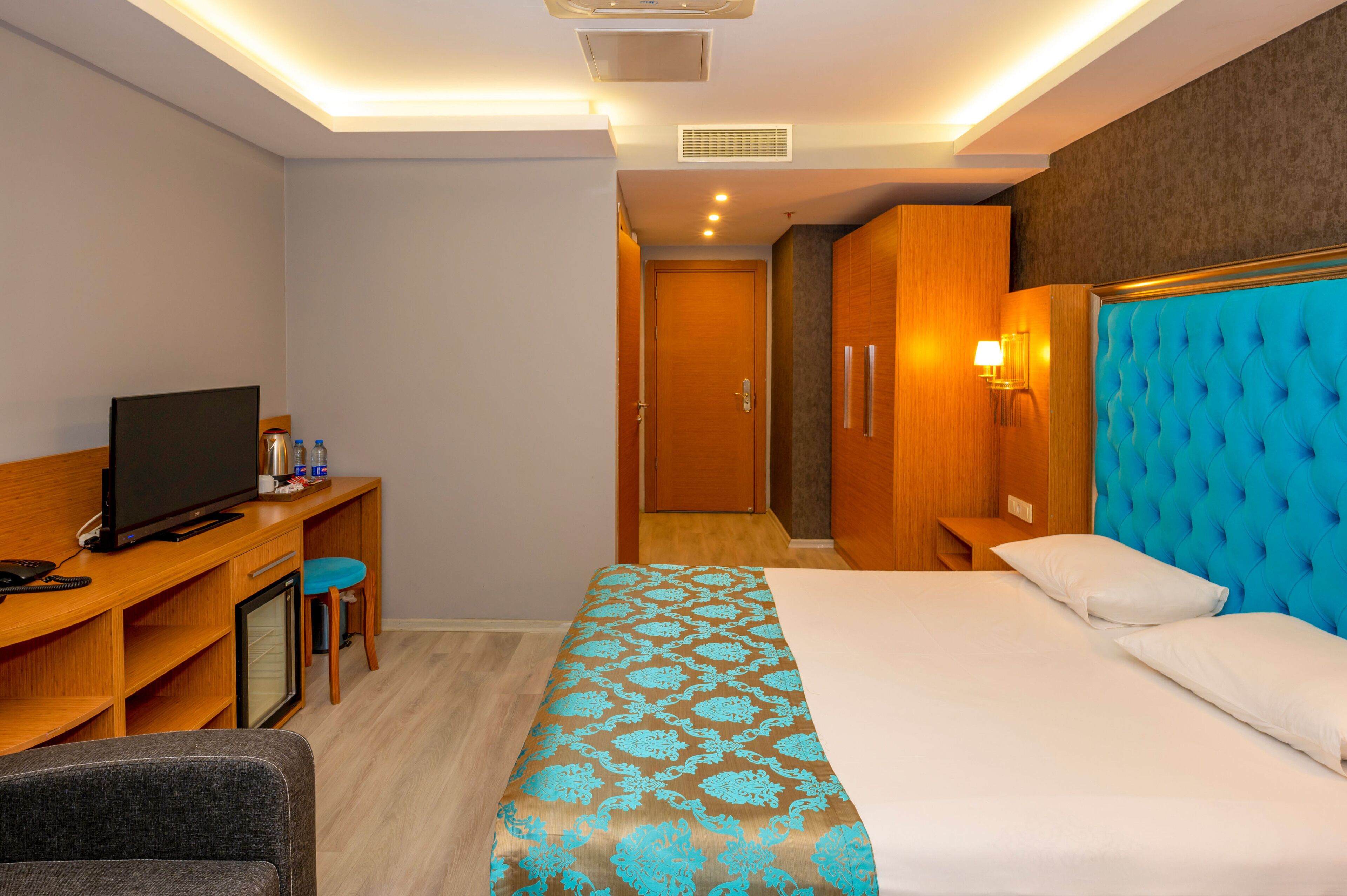 Ein Hotelzimmer mit Bett, Schreibtisch mit Fernseher, Stuhl und Kleiderschrank.