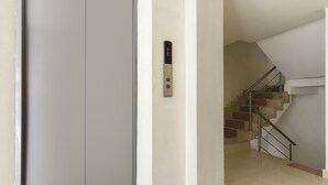 A modern elevator with a digital display, a staircase with metal railings, and a clean, minimalist interior. - 3H Hotel Centro Histórico (Medellín)