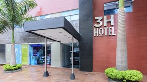 The exterior of a hotel with a covered entrance, palm trees, and a sign reading "3H HOTEL". - 3H Hotel Centro Histórico (Medellín)
