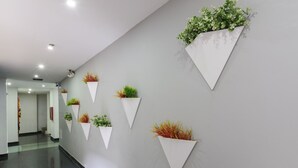 A hallway with a modern design, featuring a series of triangular planters with various plants on the wall. - 3H Hotel Centro Histórico (Medellín)