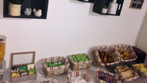A room with shelves holding plants and decorative items, and baskets containing food items. - Hotel Althea (Béziers)
