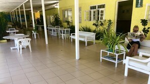 A covered outdoor seating area with white tables and chairs, surrounded by potted plants. - Sunflower Resort & Villas (St. Ann's Bay)