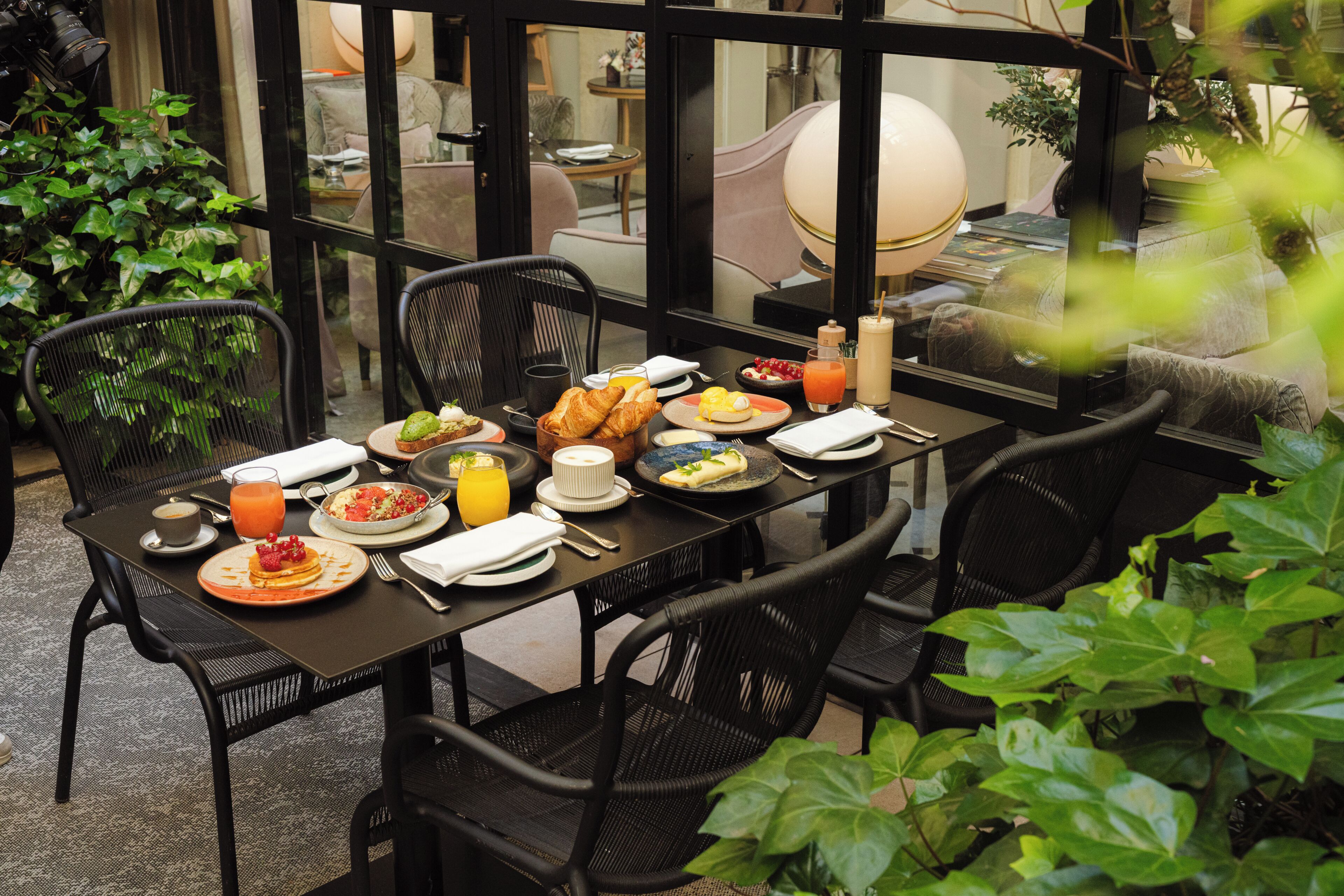 A dining table set for breakfast with plates of food, drinks, and a lamp.