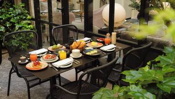 A dining table set for breakfast with plates of food, drinks, and a lamp.