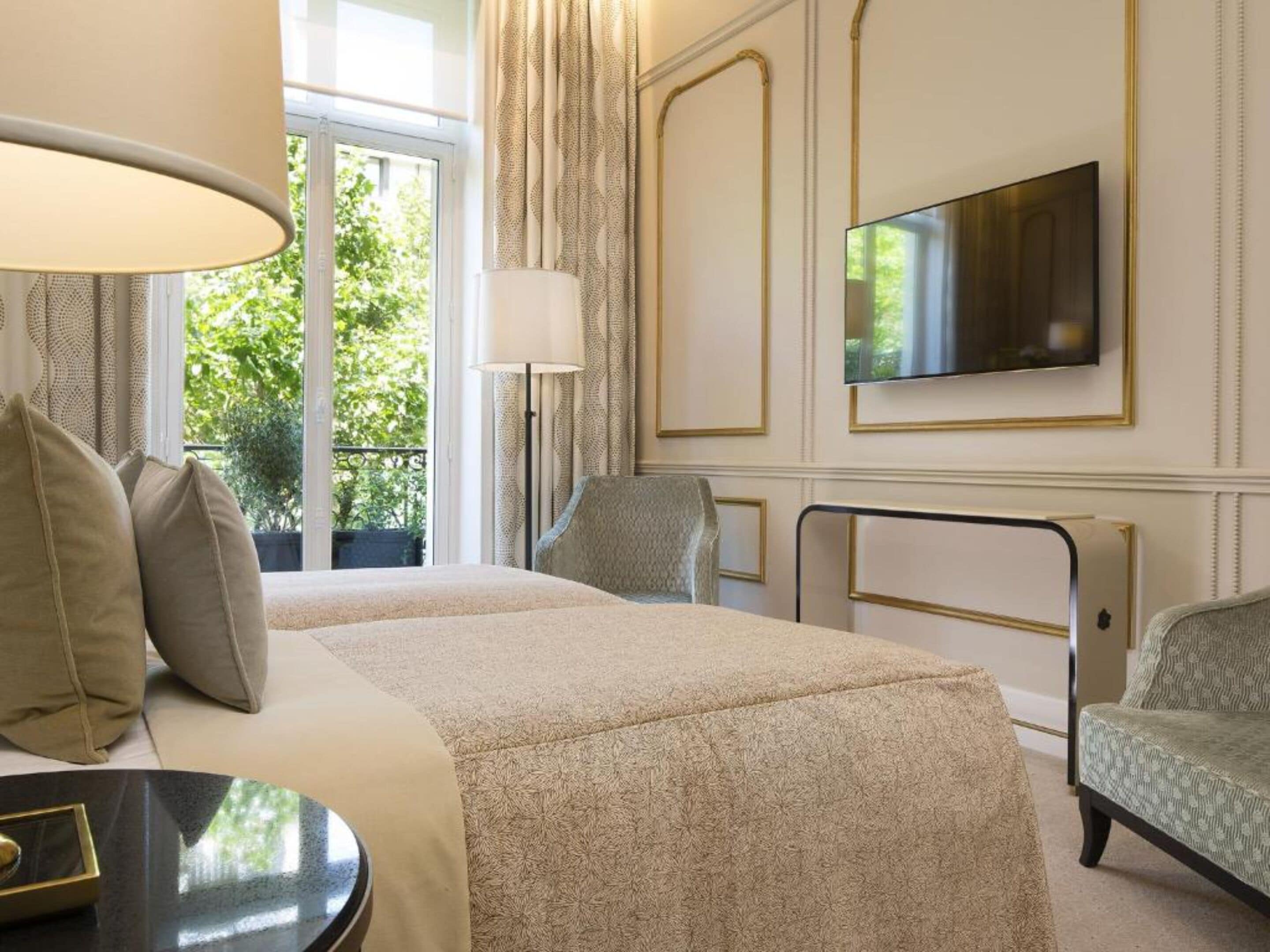 A hotel room with two beds, a TV, a desk, and a chair.