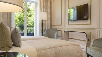 A hotel room with two beds, a TV, a desk, and a chair.