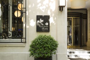 A sign for "le Narcisse Blanc Hotel & Spa Paris" with a potted plant in front. - Hotel Le Narcisse Blanc & Spa (Paris)
