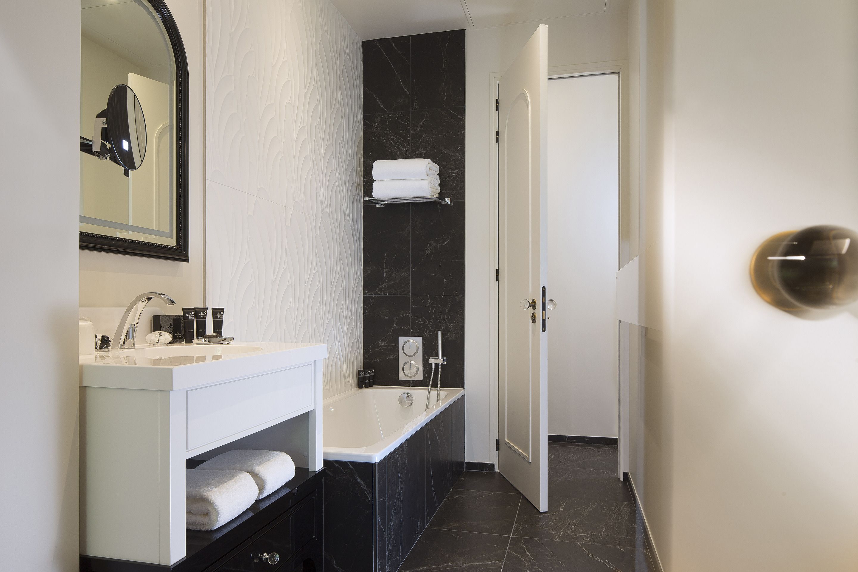 A modern bathroom with a white vanity, a bathtub, and a mirror.