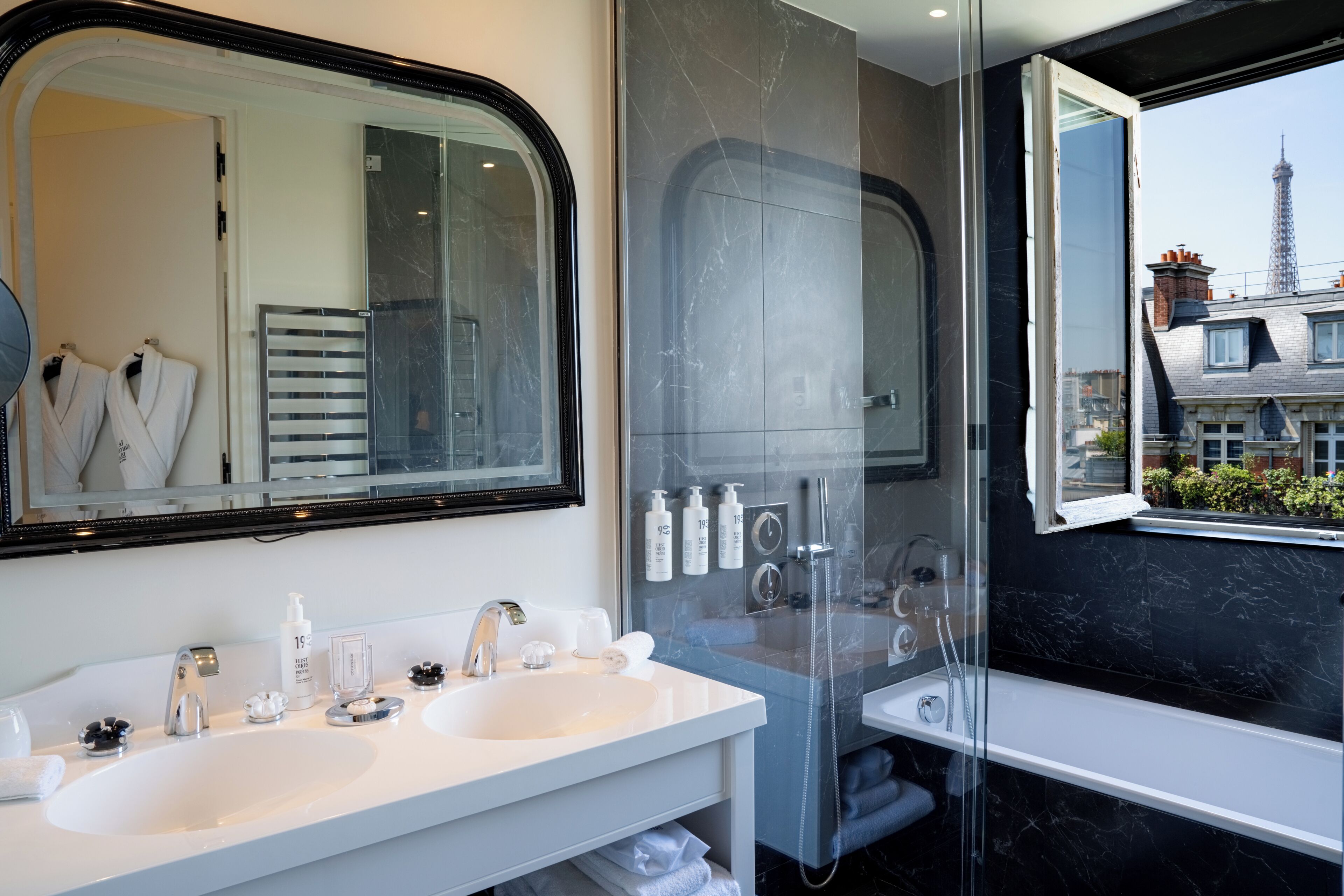 A modern bathroom with two sinks, a large mirror, and a shower.