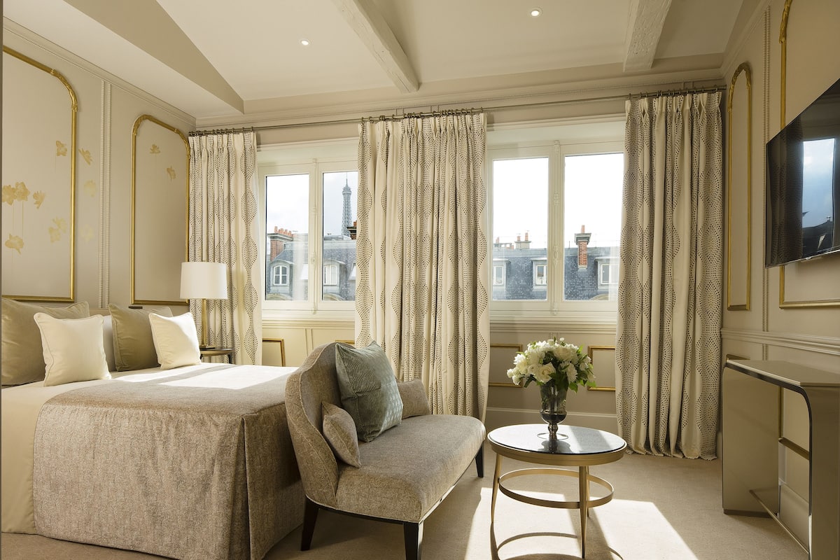 Una habitación de hotel con una cama grande, un sofá, una mesita y un televisor.