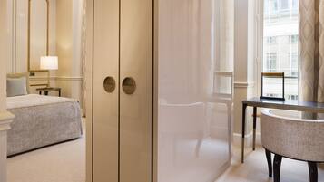 A hotel room with a bed, a desk, a chair, a mirror, and a wardrobe.