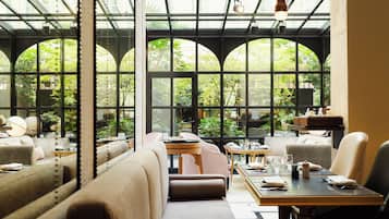 A restaurant with high ceilings, large windows, and a variety of seating arrangements including booths and tables.