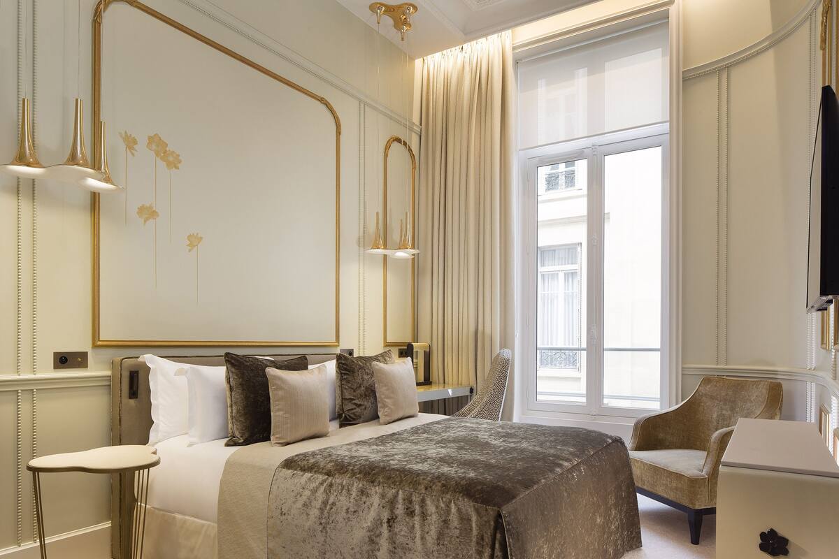 Una habitación de hotel con una cama grande, una silla, un escritorio y un ventanal amplio.