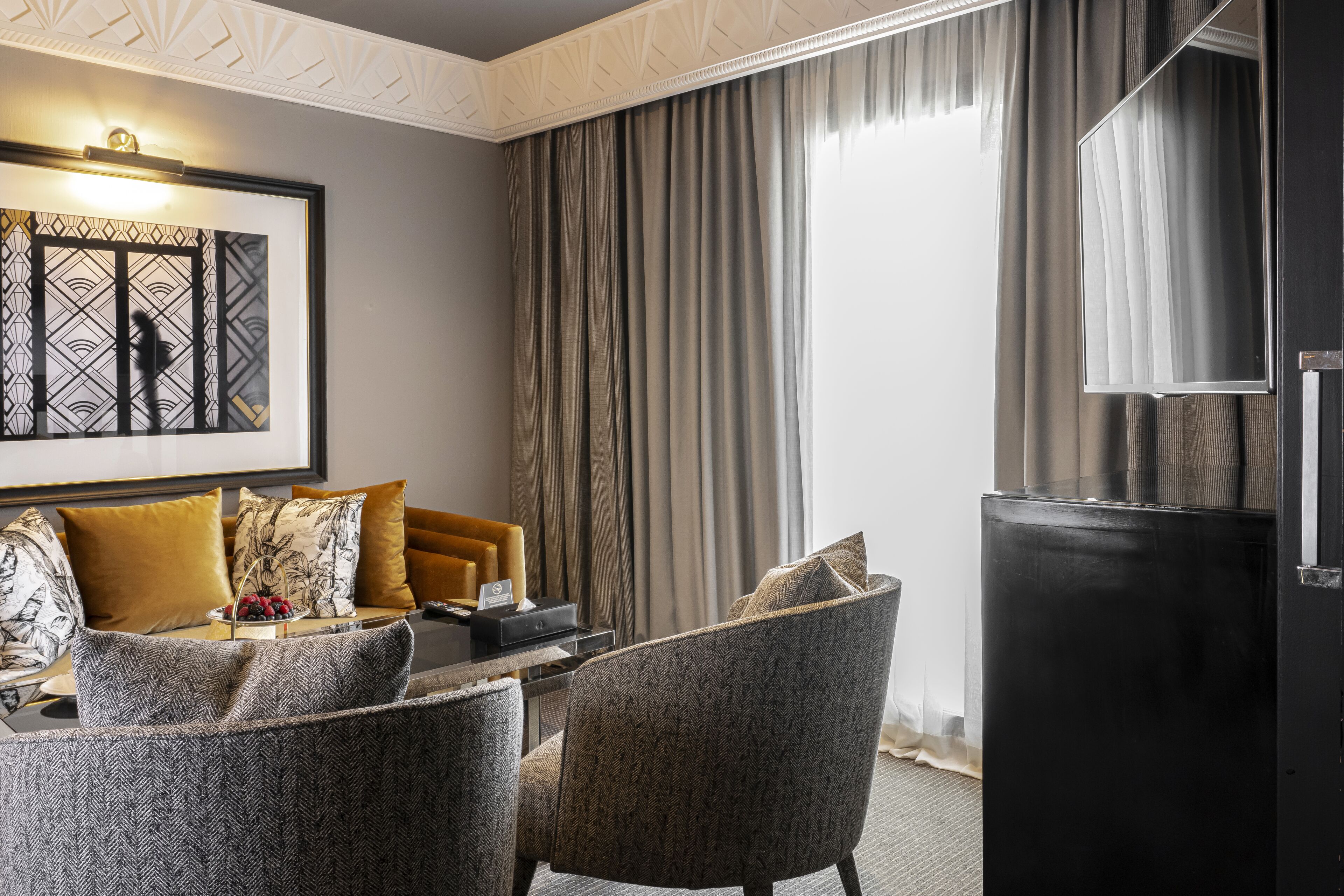A modern hotel room with a sofa set, a dining table, and a large mirror.