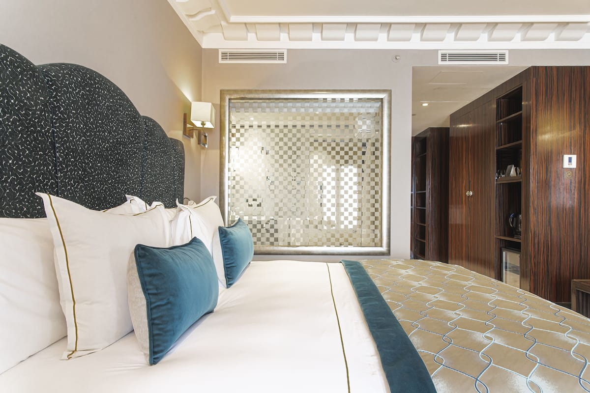 A bedroom with a large bed, a headboard, and a wardrobe.