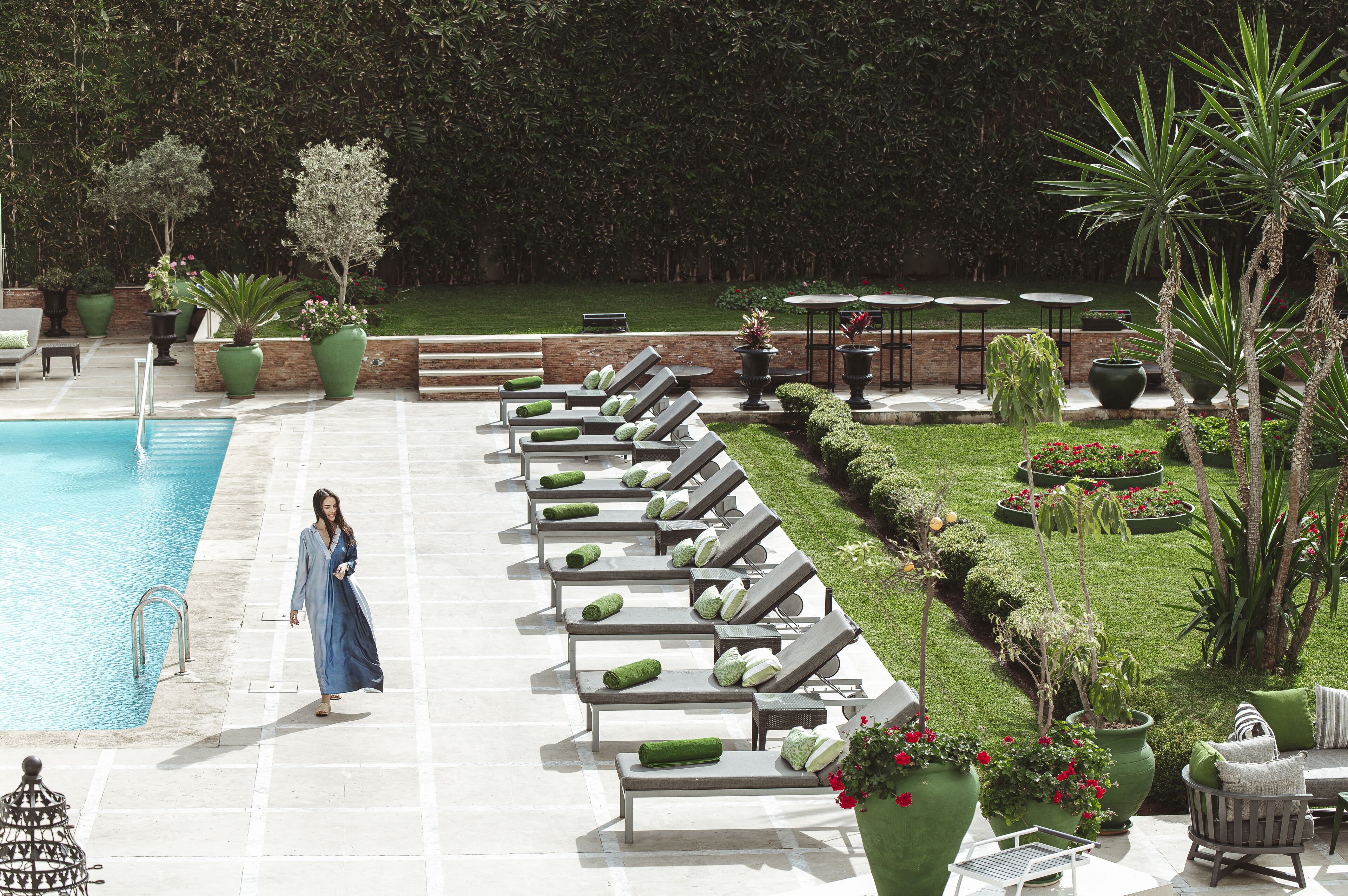 A poolside area with lounge chairs, a pool, and a well-maintained garden.