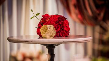 Une table ornée d’un vase décoratif contenant des roses rouges et d’un objet géométrique.