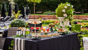 Montaje de bufé al aire libre con diversas opciones de comida y un centro de mesa decorativo.