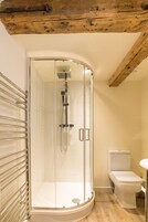 A modern bathroom with a glass-enclosed shower, a toilet, and a sink.