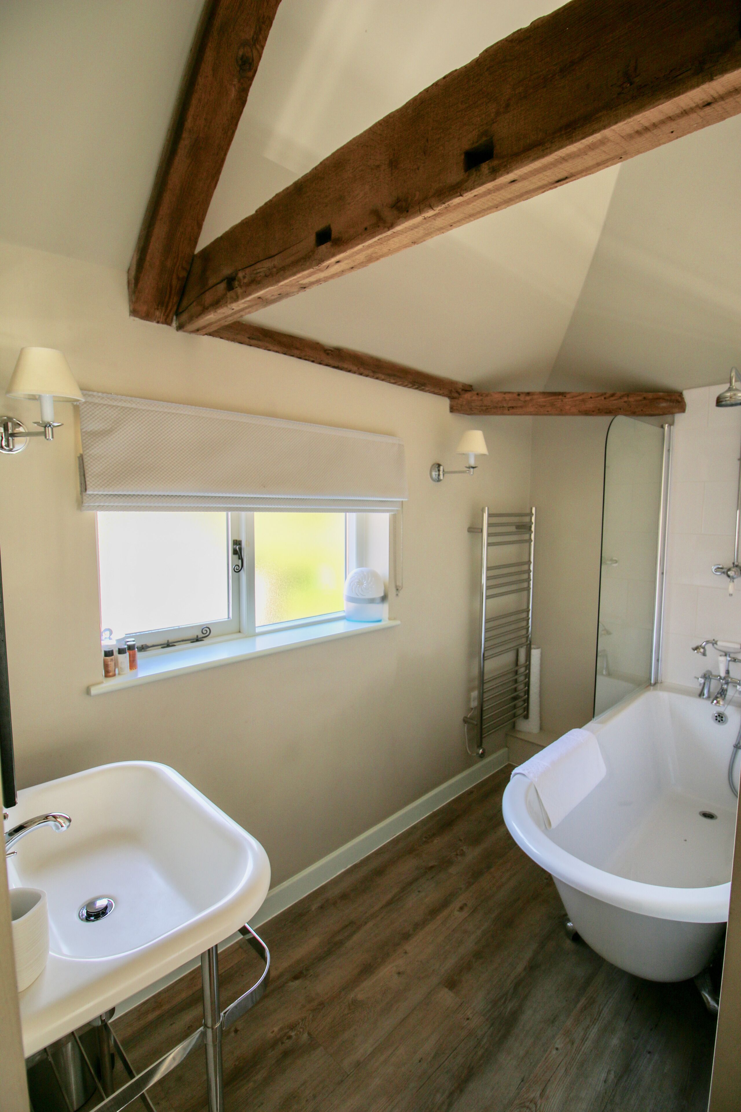 A bathroom with a wooden ceiling, a window with a view, a sink, and a bathtub.