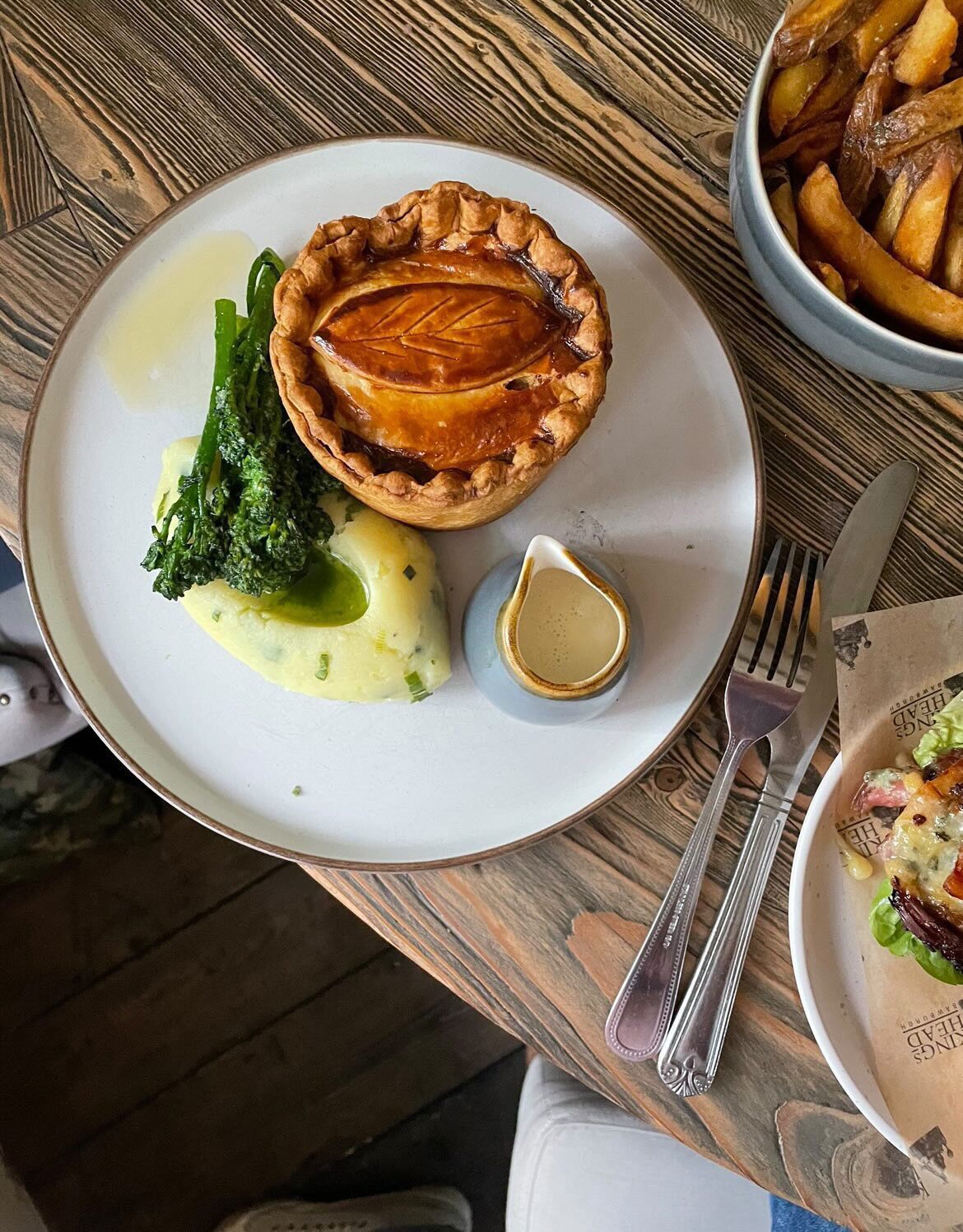 A plate with a meat pie, mashed potatoes, and steamed broccoli.