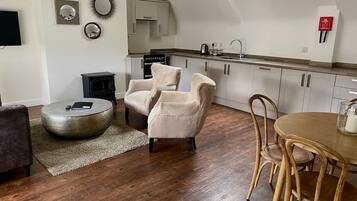 A modern living room with a fireplace, round ottoman, and a dining table with chairs.