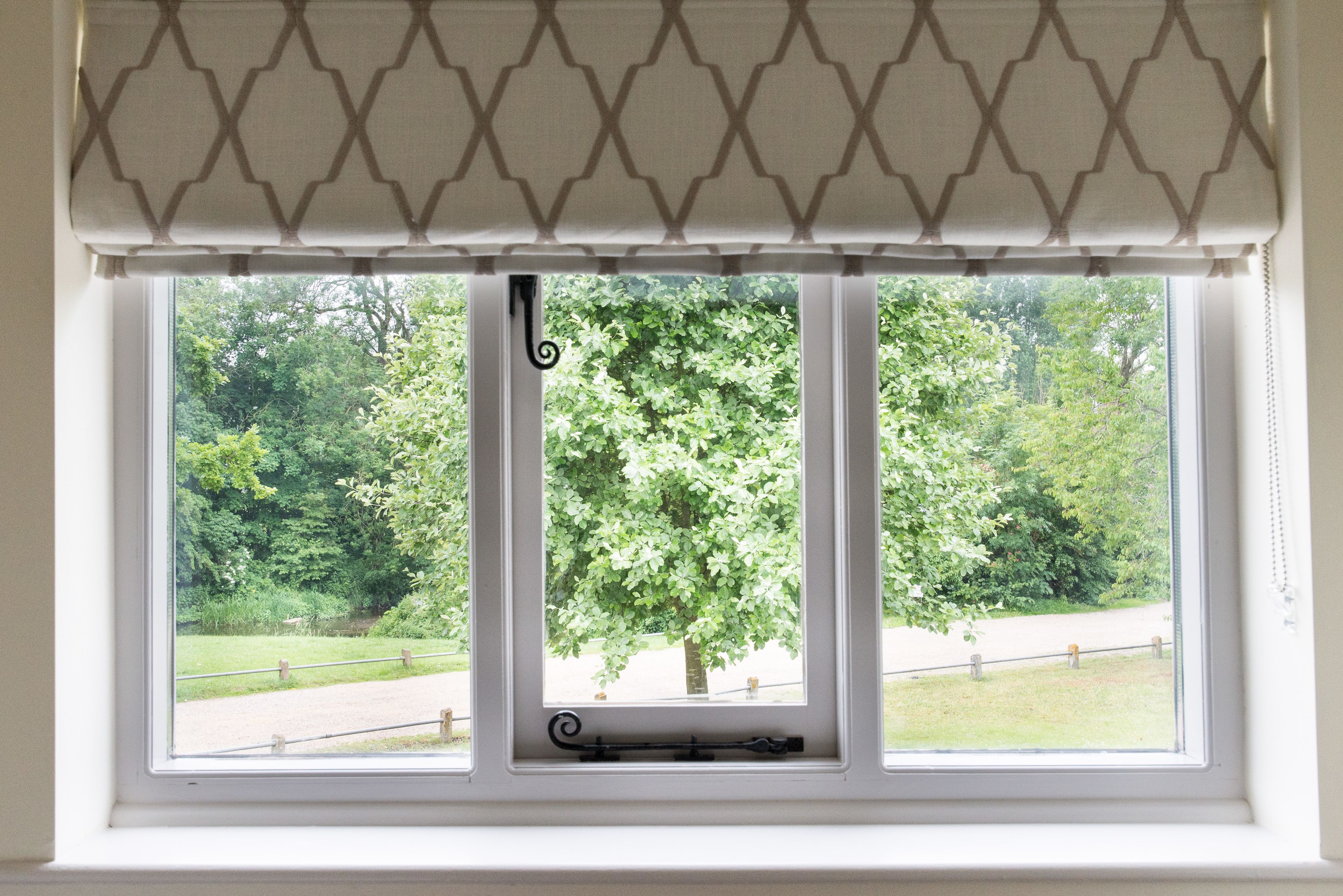 Una ventana con marco blanco y un cortinero estampado.