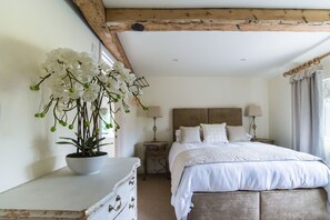 A bedroom with a bed, bedside tables, a lamp, and a potted orchid plant.
