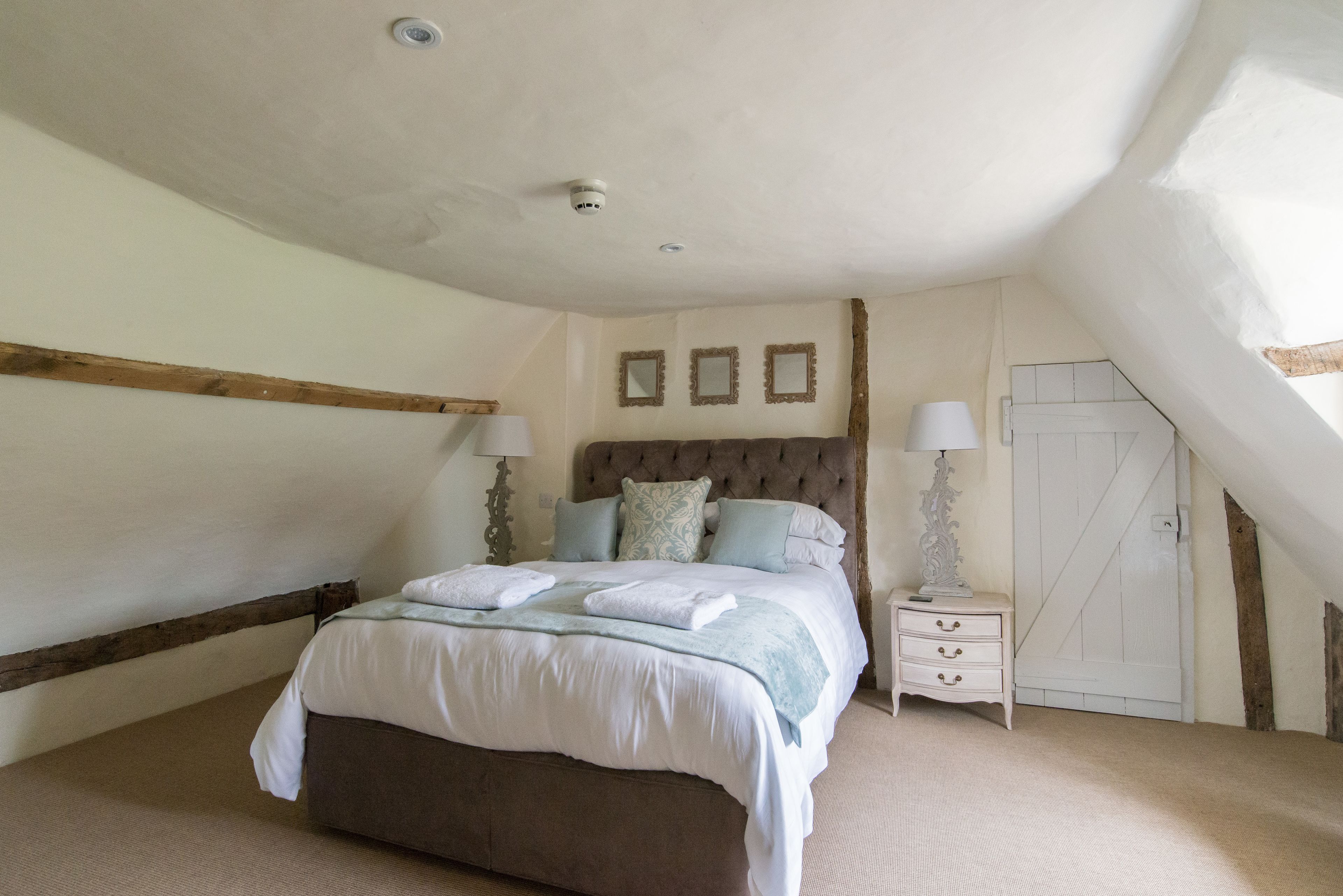 A bedroom with a large bed, a nightstand, a dresser, and a door.