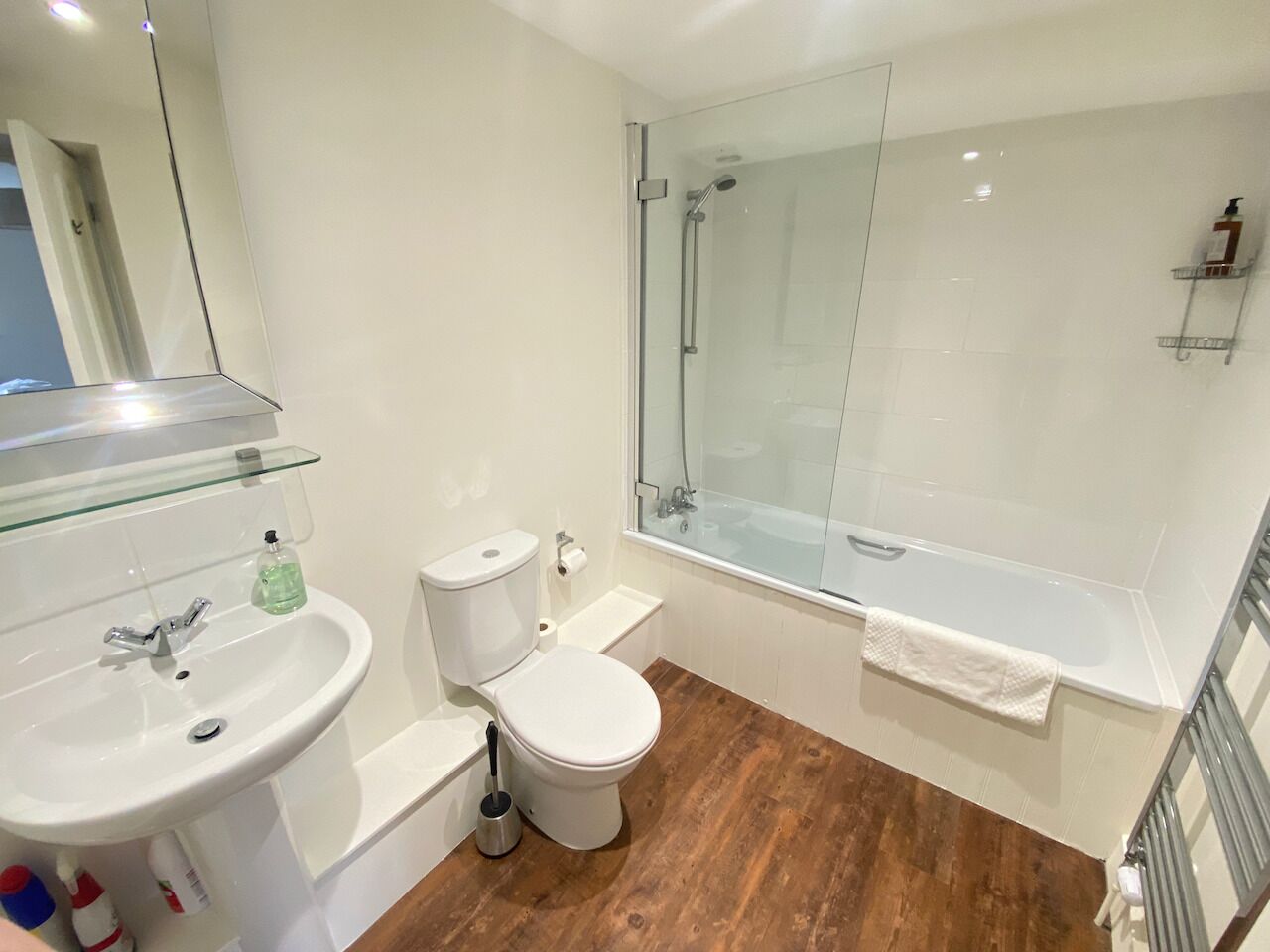 A modern bathroom with a glass-enclosed shower, a white sink, and a toilet.