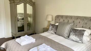 A neatly made bed with a large mirror and a lamp beside it.