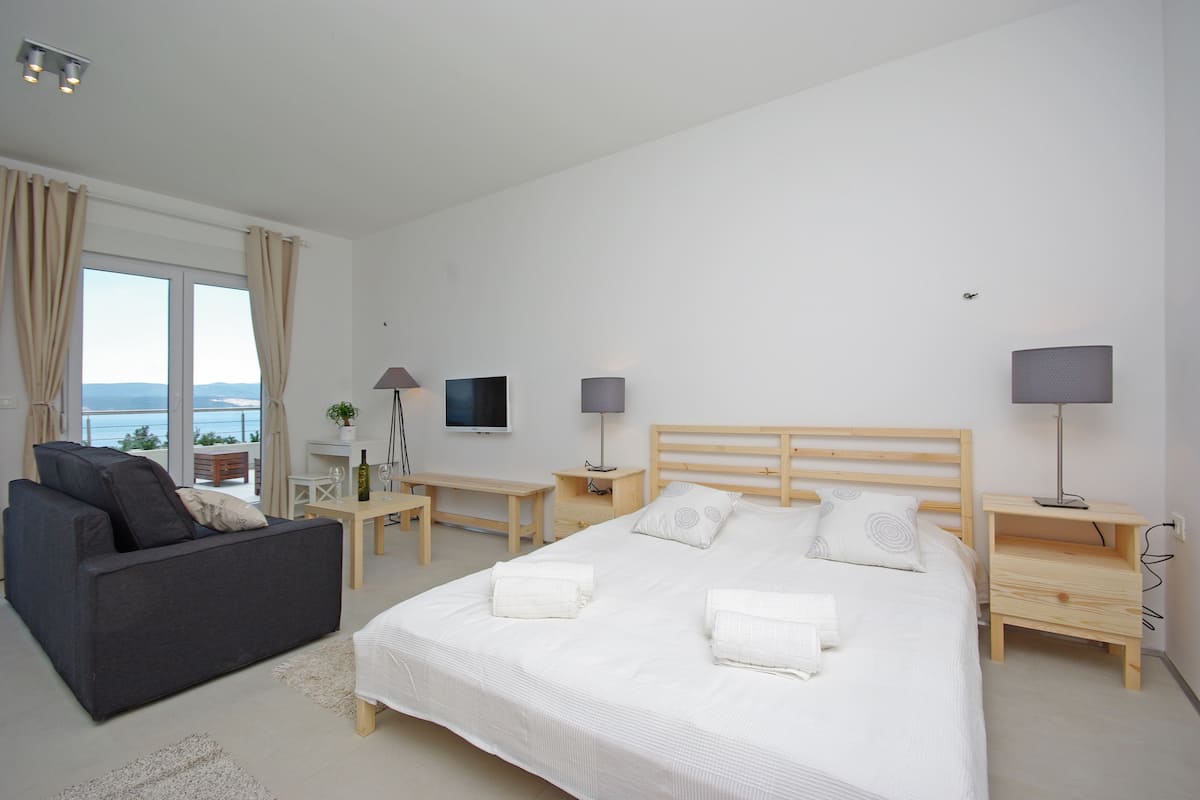 Ein modernes Hotelzimmer mit einem großen Bett, einer Couch, einem Schreibtisch und einem Fernseher.