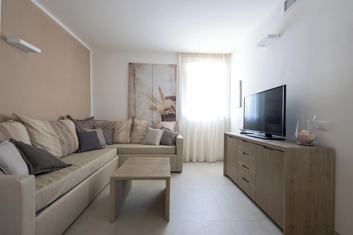 Una sala de estar con sofá, mesa de centro, televisor y mueble.