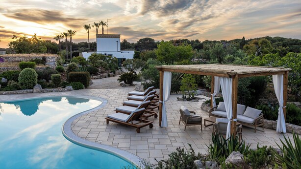 Ein Poolbereich mit Liegestühlen, einer Holzpergola und Blick auf die umliegende Landschaft.
