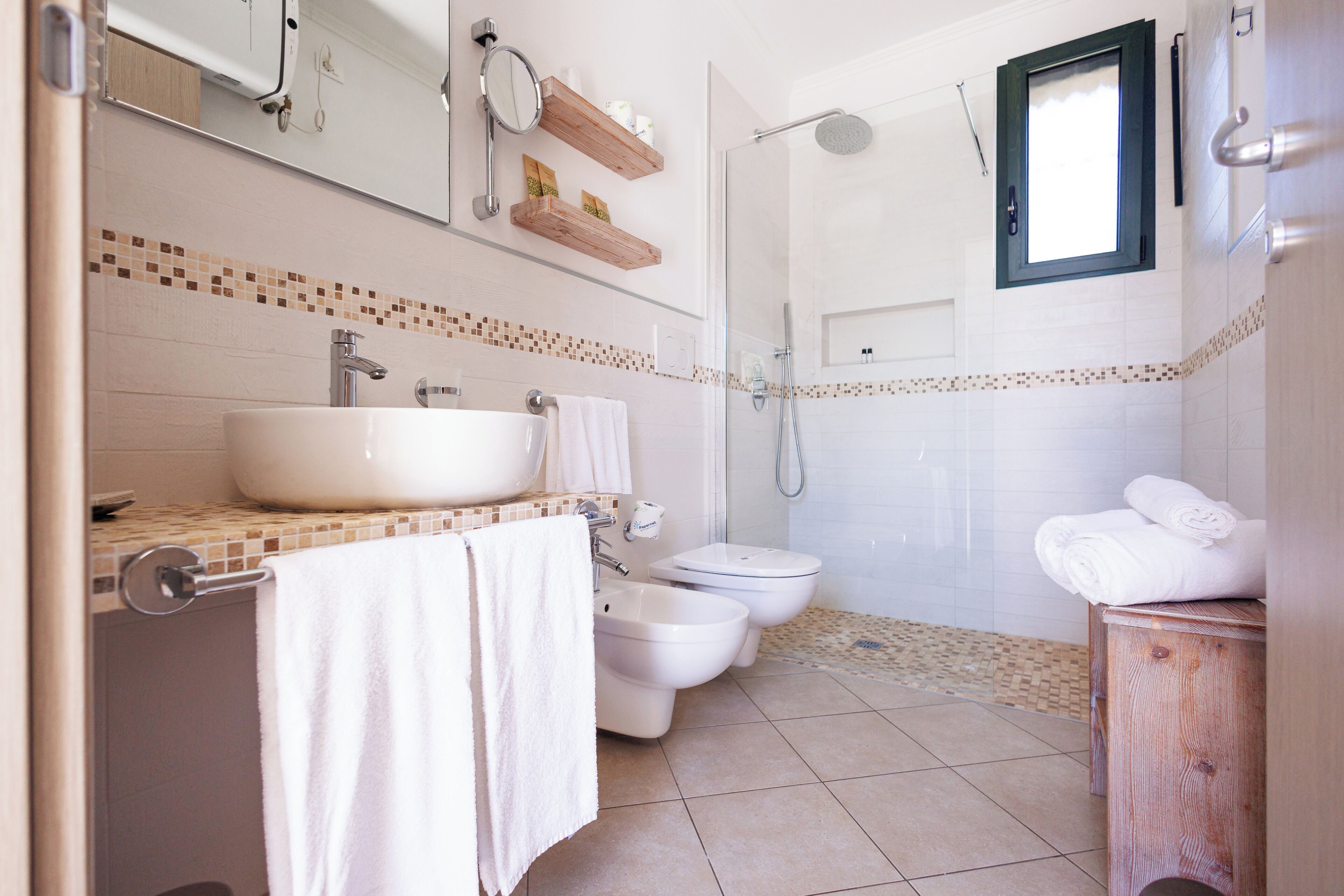 A bathroom with a large sink, bidet, toilet, and shower.