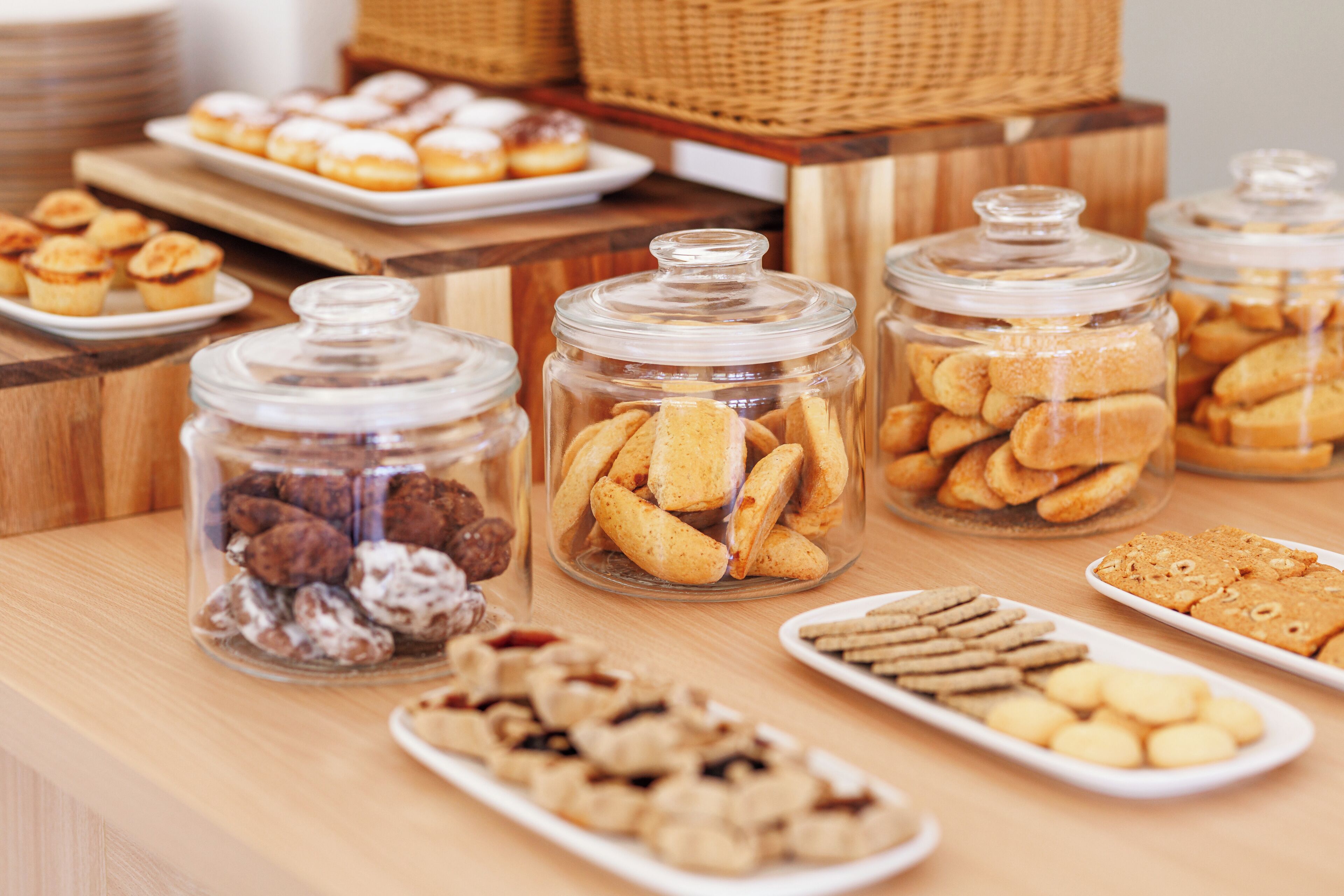 A variety of baked goods displayed in glass jars and on plates, suggesting a bakery or cafe setting.