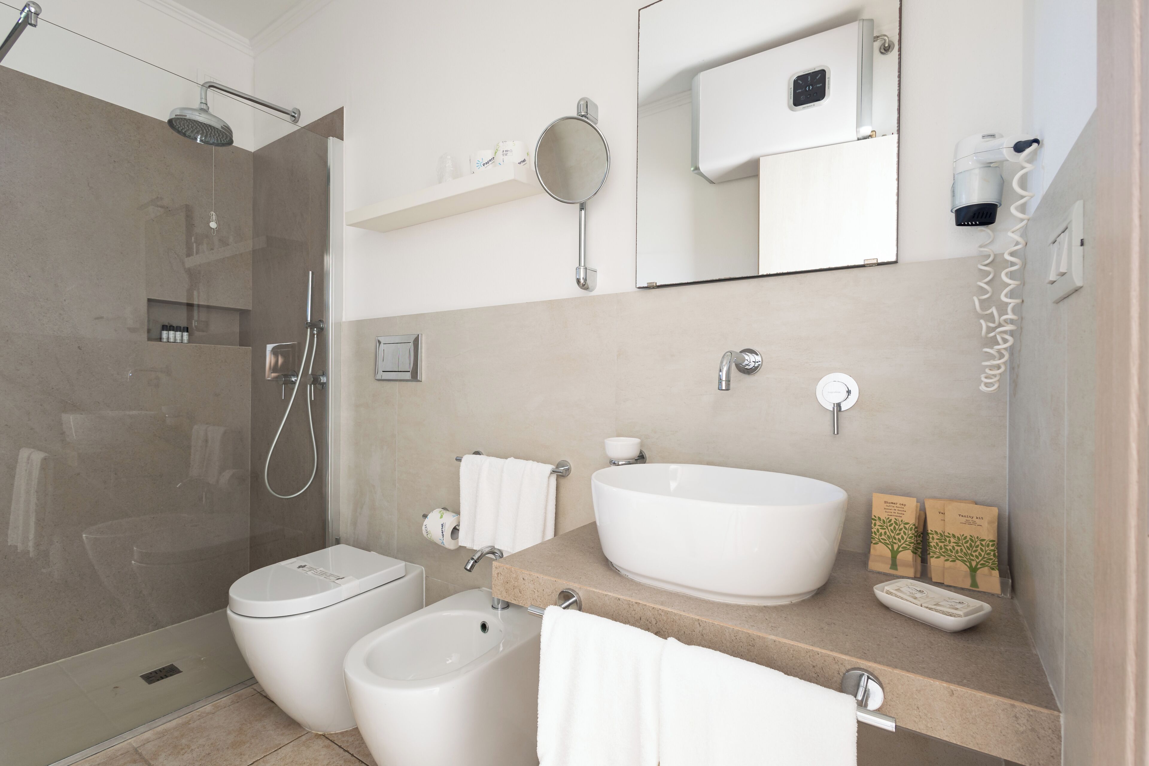 A modern bathroom with a shower, bidet, sink, and mirror.