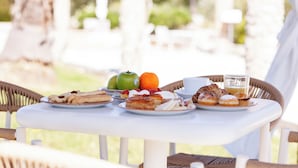 Una mesa con alimentos para el desayuno, como pasteles, frutas y un vaso de jugo.