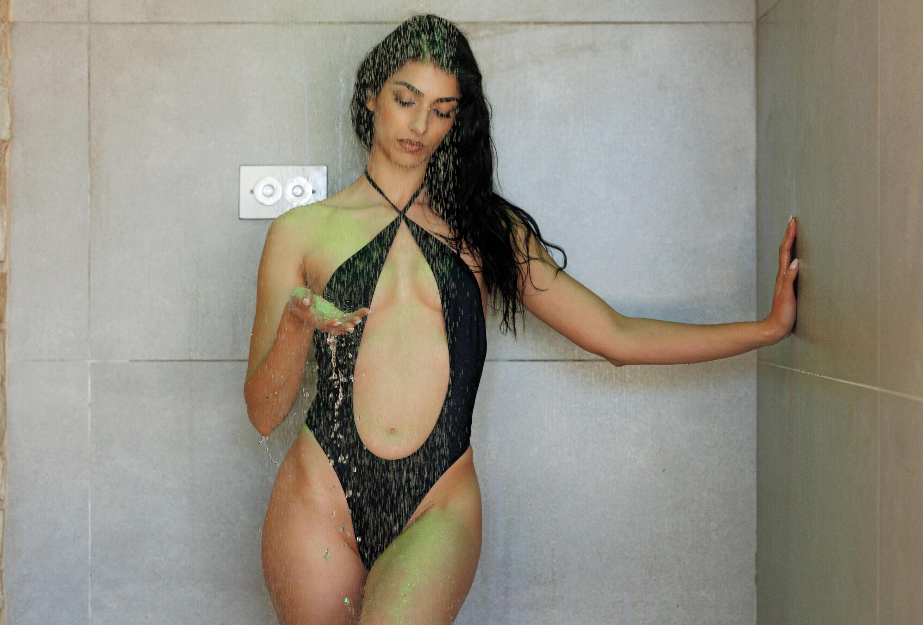 Una persona en traje de baño de pie en una habitación con una pared lisa y un interruptor de luz.