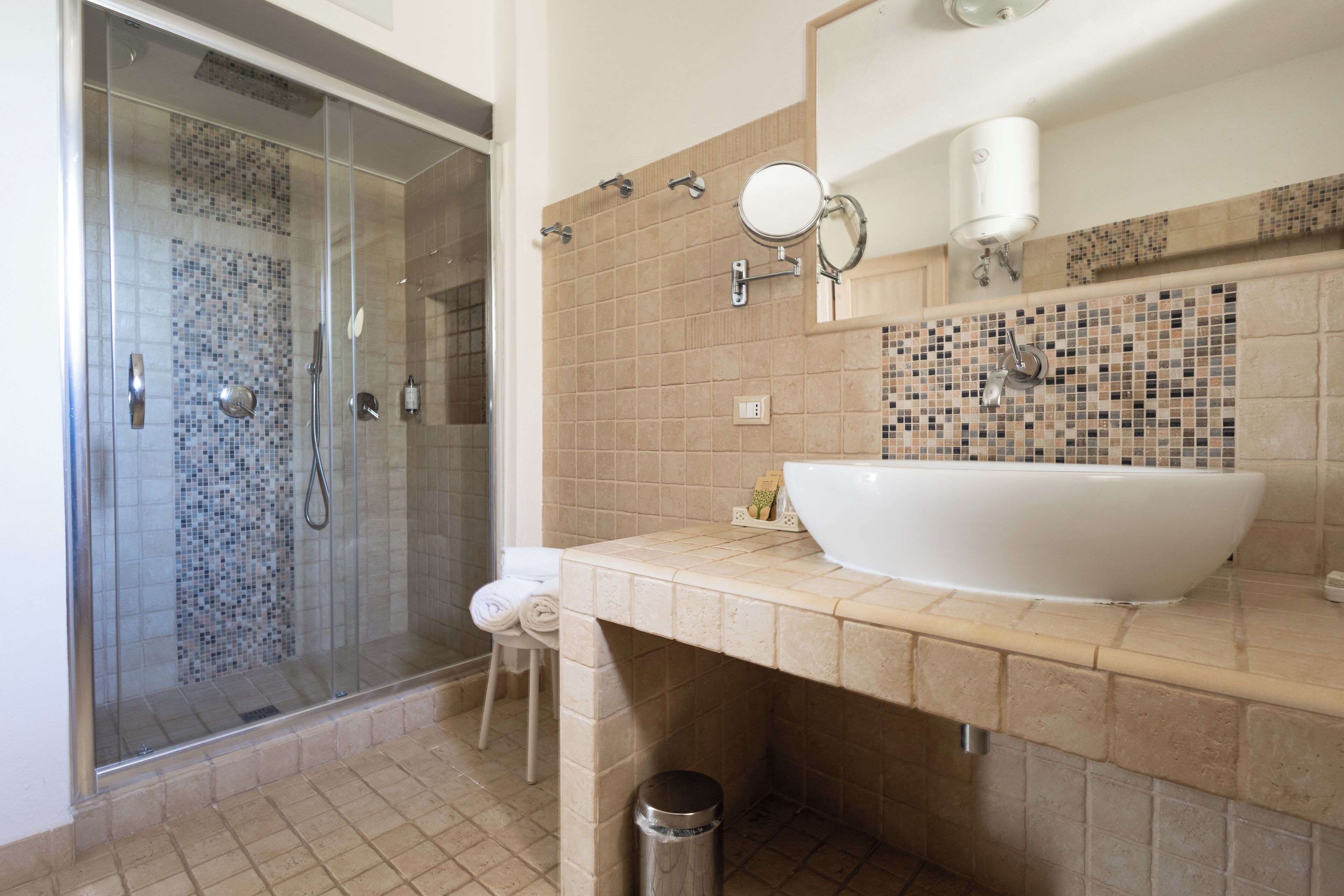 Un baño con ducha de vidrio, un lavamanos grande de color blanco y un salpicadero de azulejos.