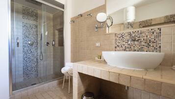 Un baño con ducha de vidrio, un lavamanos grande de color blanco y un salpicadero de azulejos.