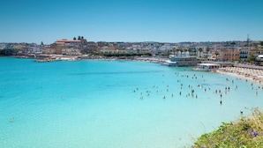Eine Küstenstadt mit klarem, blauem Meer, Strand und Häusern entlang der Küste.