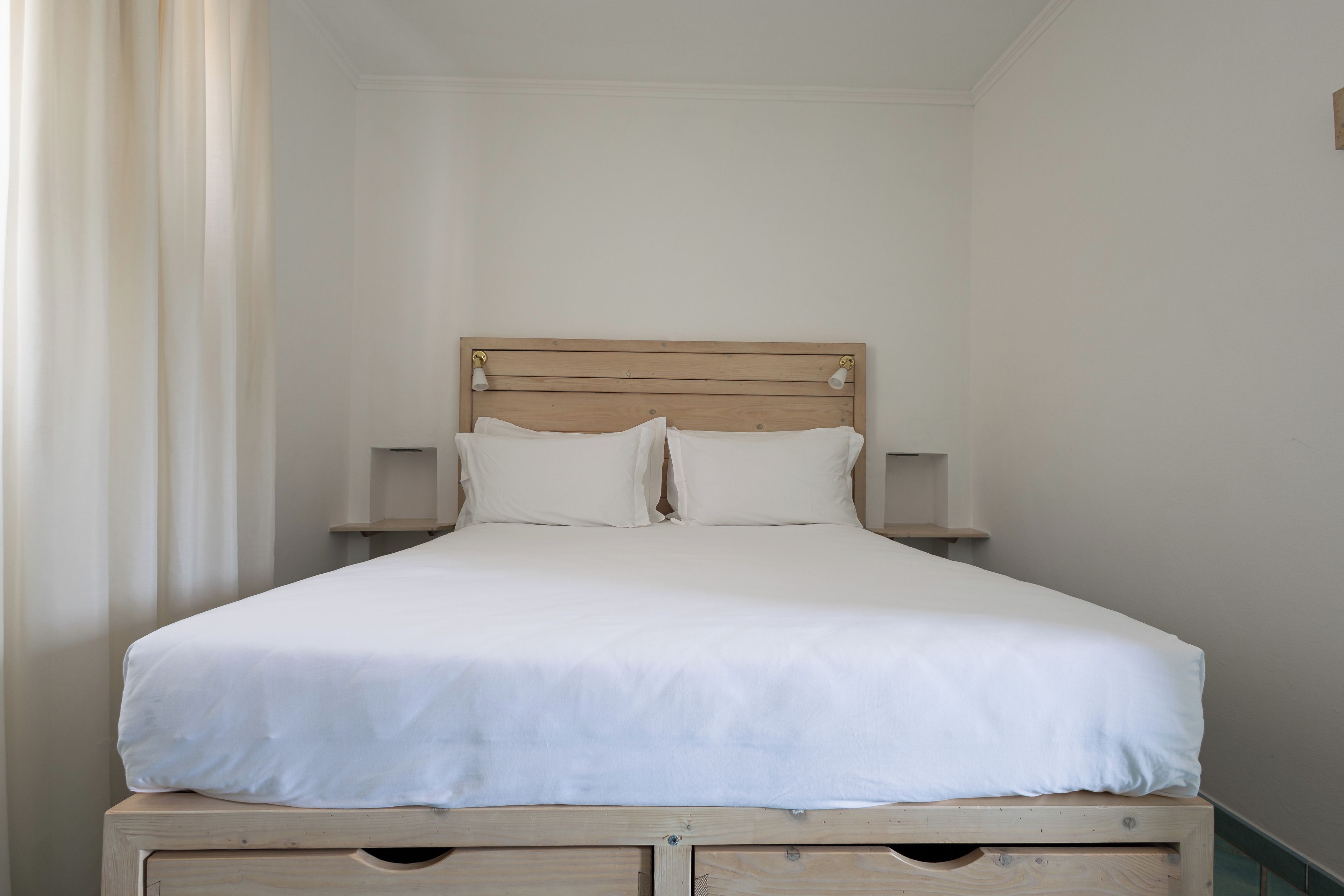 A single bed with a wooden headboard, two bedside tables, and a white bedspread.