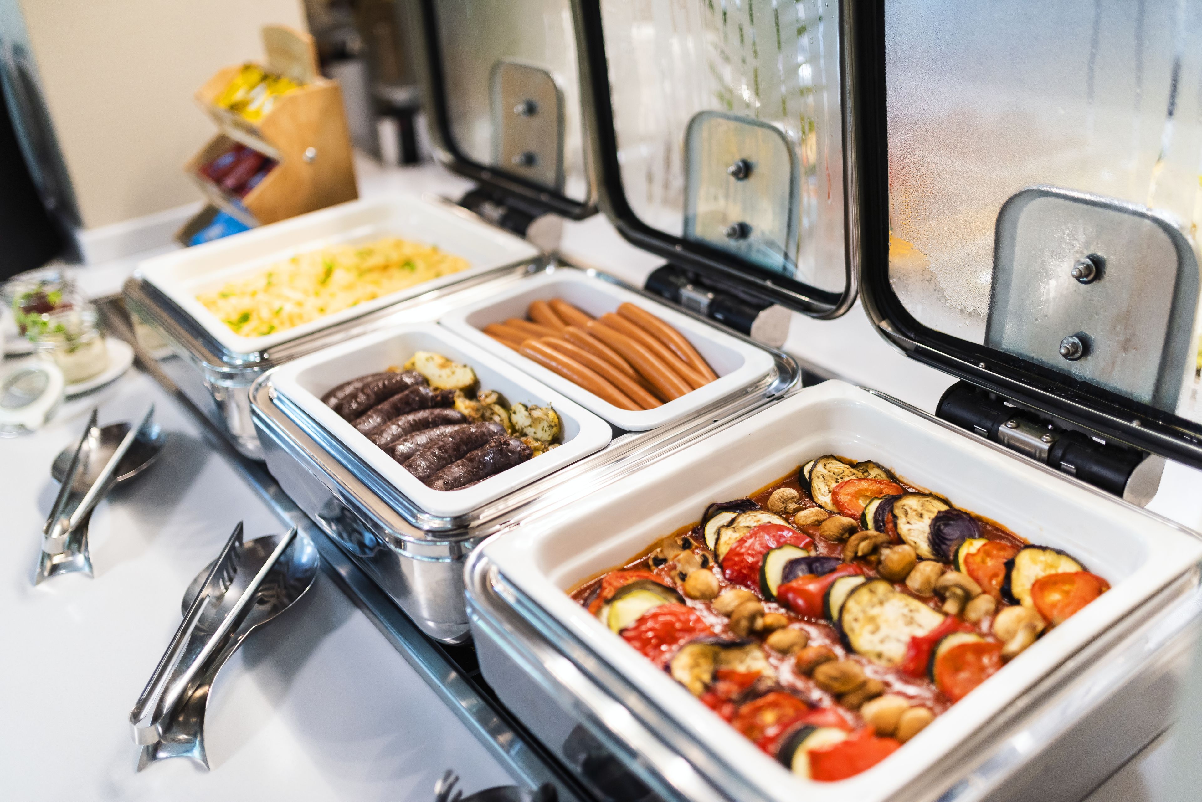 Ein Buffet mit verschiedenen Speisen, darunter Fleisch, Gemüse und Soßen.