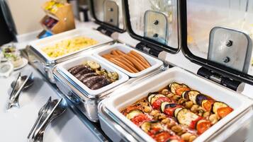 Ein Buffet mit verschiedenen Speisen, darunter Fleisch, Gemüse und Soßen.