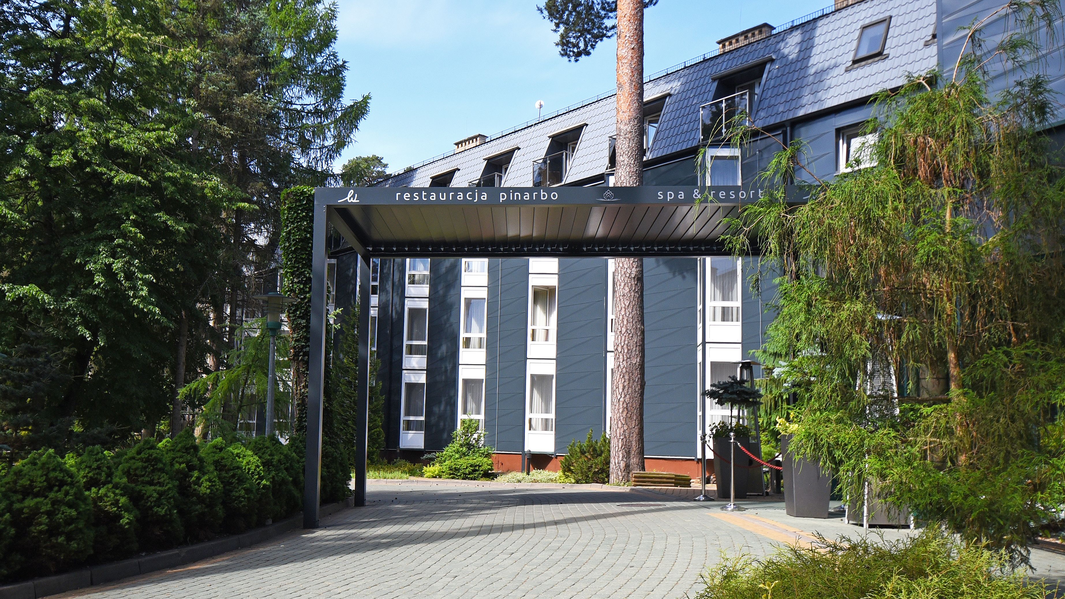 A building entrance with a sign reading "restauracja pinarbo spa & resort".