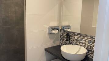 A modern bathroom with a large mirror, a white sink, and a towel rack.